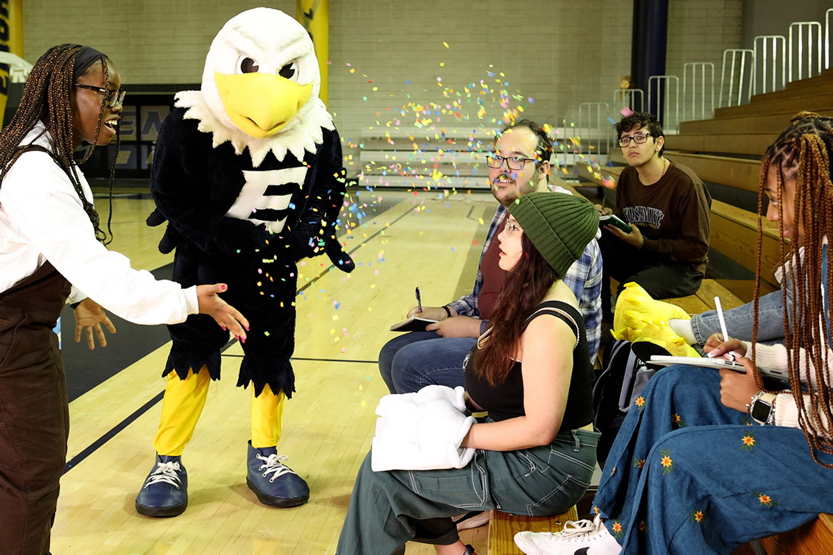 Emory University mascot Swoop with students sitting on bleachers